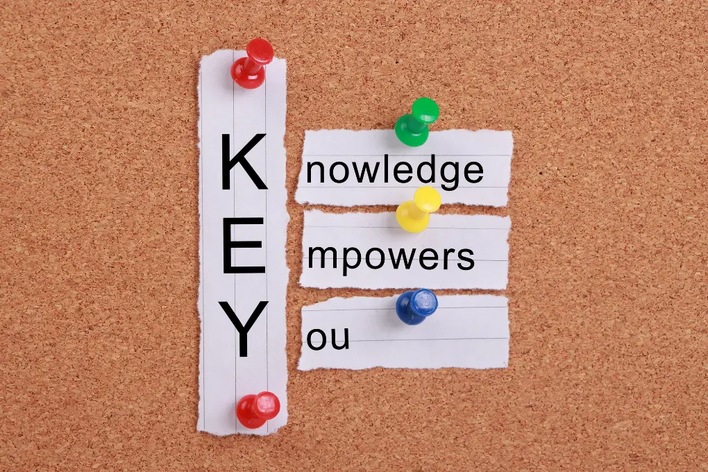 Pieces of paper pinned onto a corkboard with colorful thumbtacks. The Left paper displays the word KEY vertically, while the right papers reads knowledge empowers you