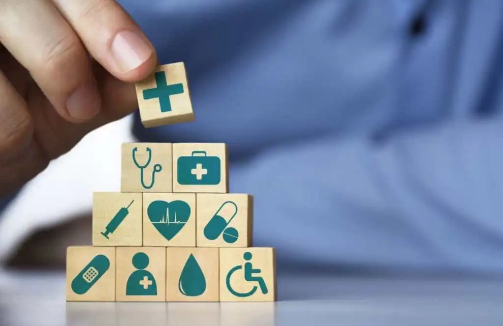 Medical health insurance concept. Men's hand arranging front view wood blocks with healthcare medicine icons