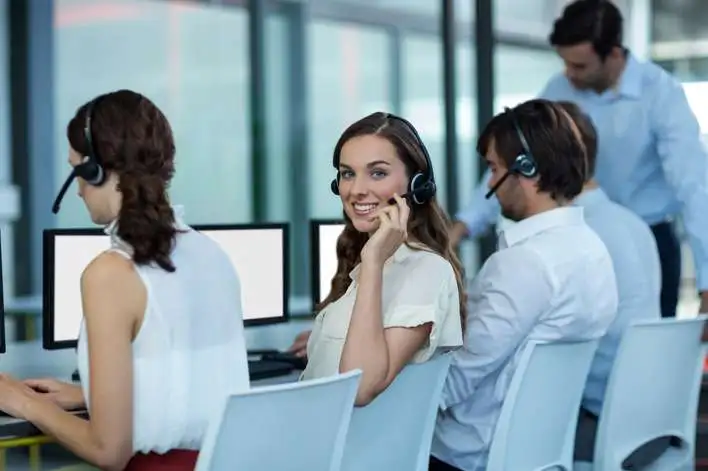 Telecalling team staff working in an office, a girl is looking straight and smiling while working 